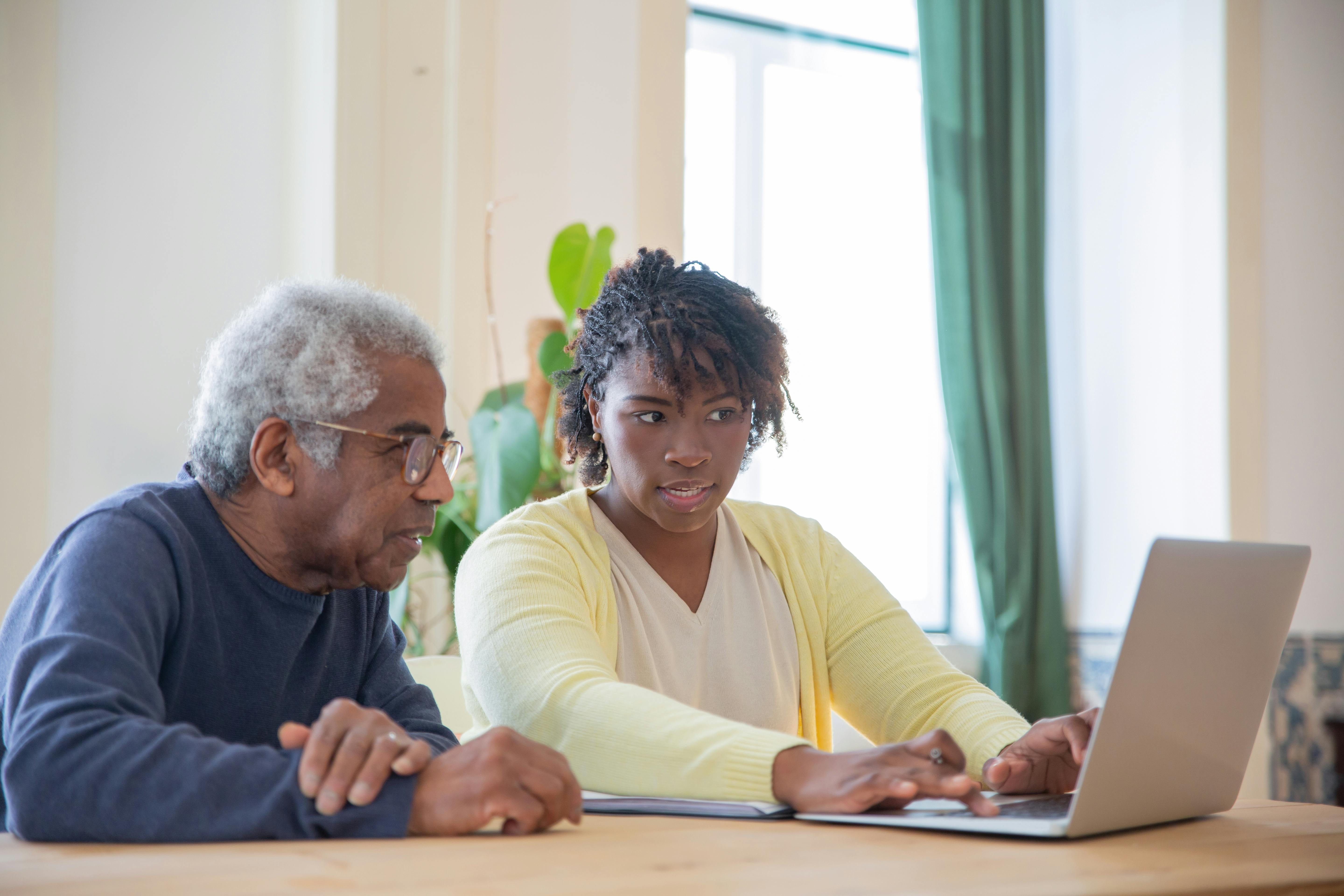 Caregiver assisting an older adult on a laptop