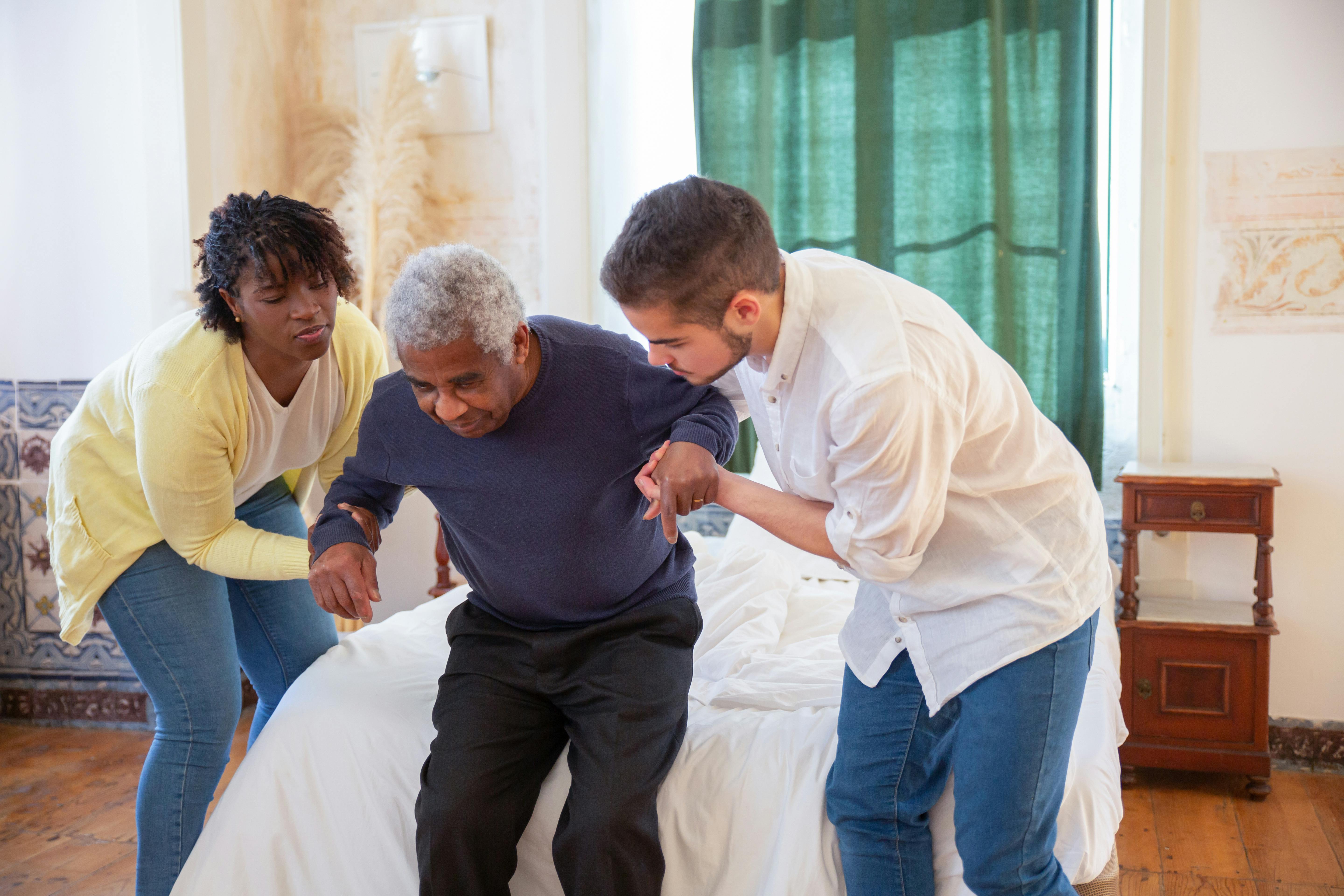 Caregivers helping a senior man stand up safely